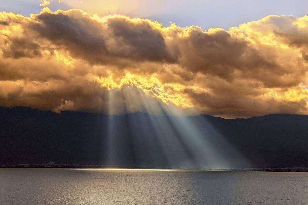 Sun rays breaking through golden clouds, symbolizing emotional clarity after a low vibration mood.