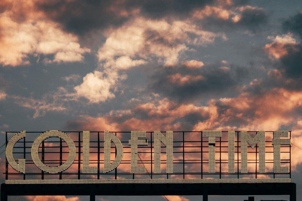 Golden Time neon sign against a sunset sky symbolizing a fresh start and a higher money vibration.