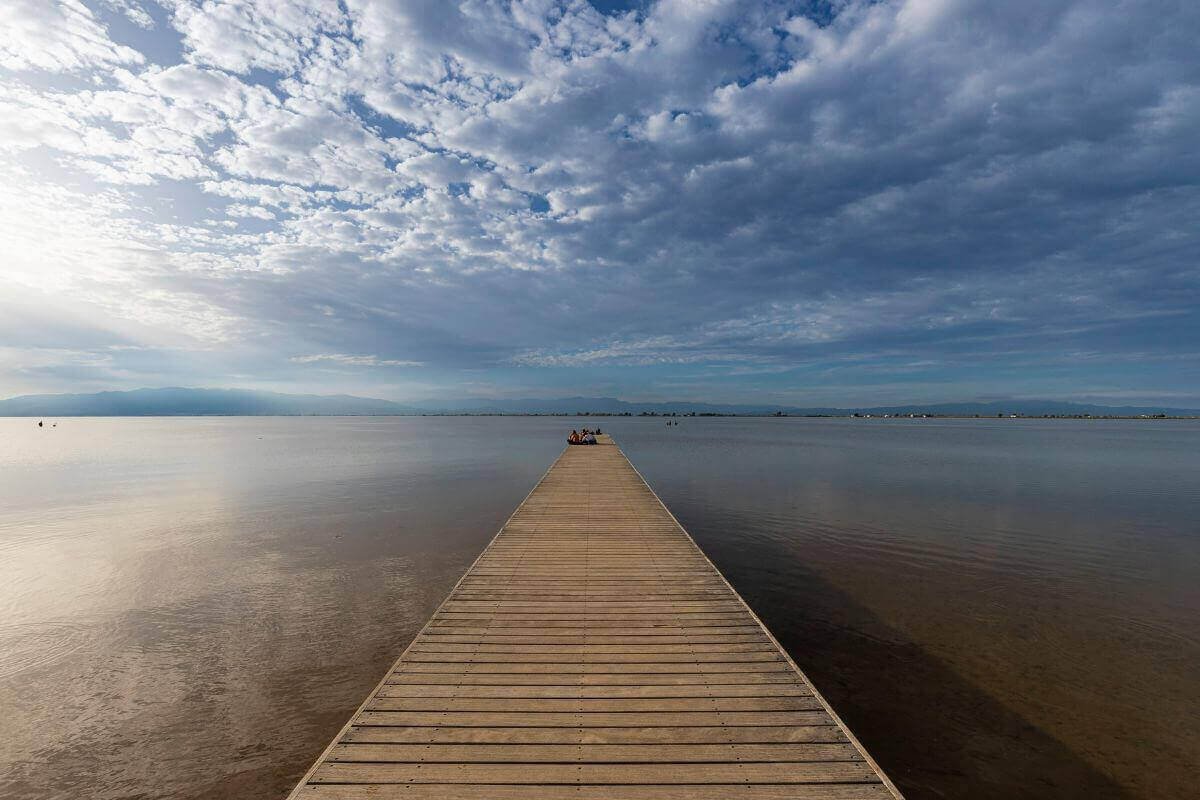A calm wooden pathway leading into still water under an open sky, symbolizing spiritual clarity, energetic alignment, and inner openness.