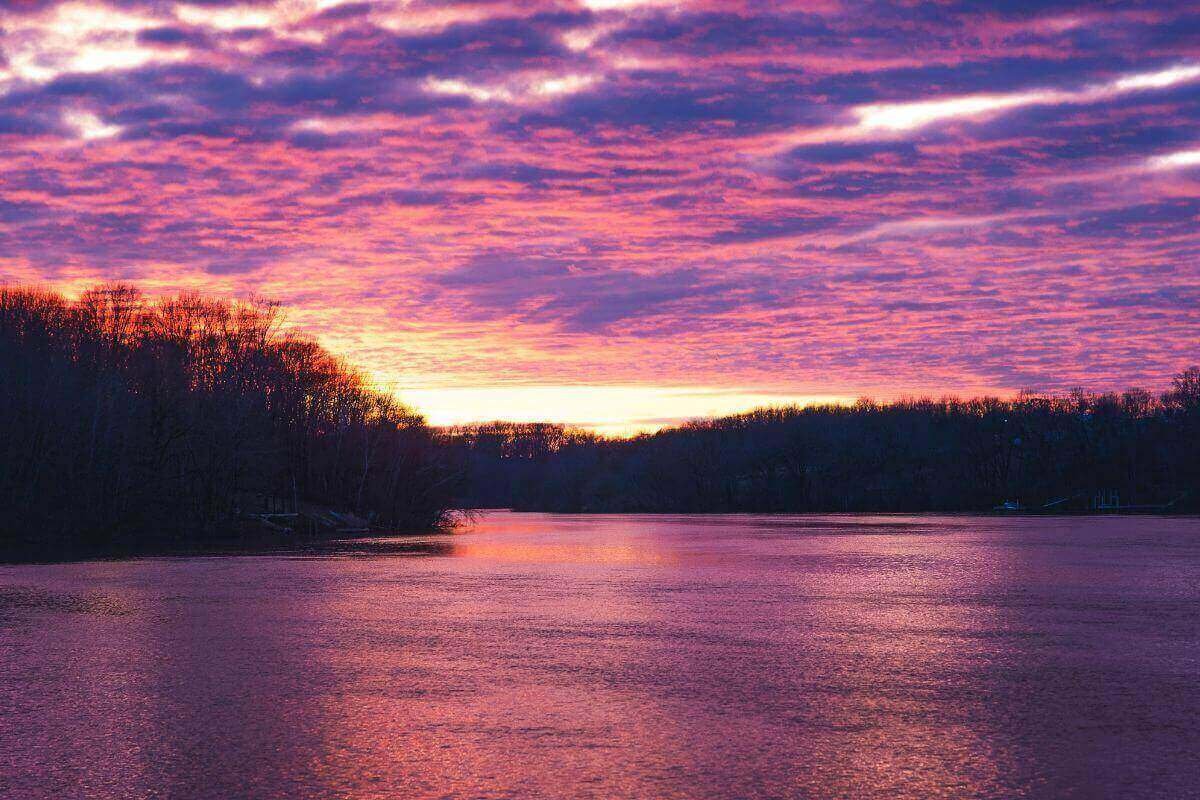 Purple and pink sunset reflecting over calm water, symbolizing money vibration, emotional healing, and the shift from low to higher energy.