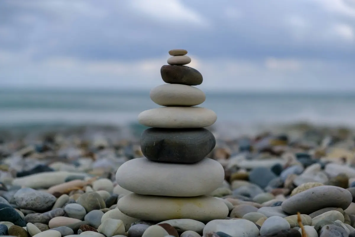 A stack of smooth, balanced stones on a pebble beach, representing emotional steadiness, resilience, and a high-frequency state of inner harmony