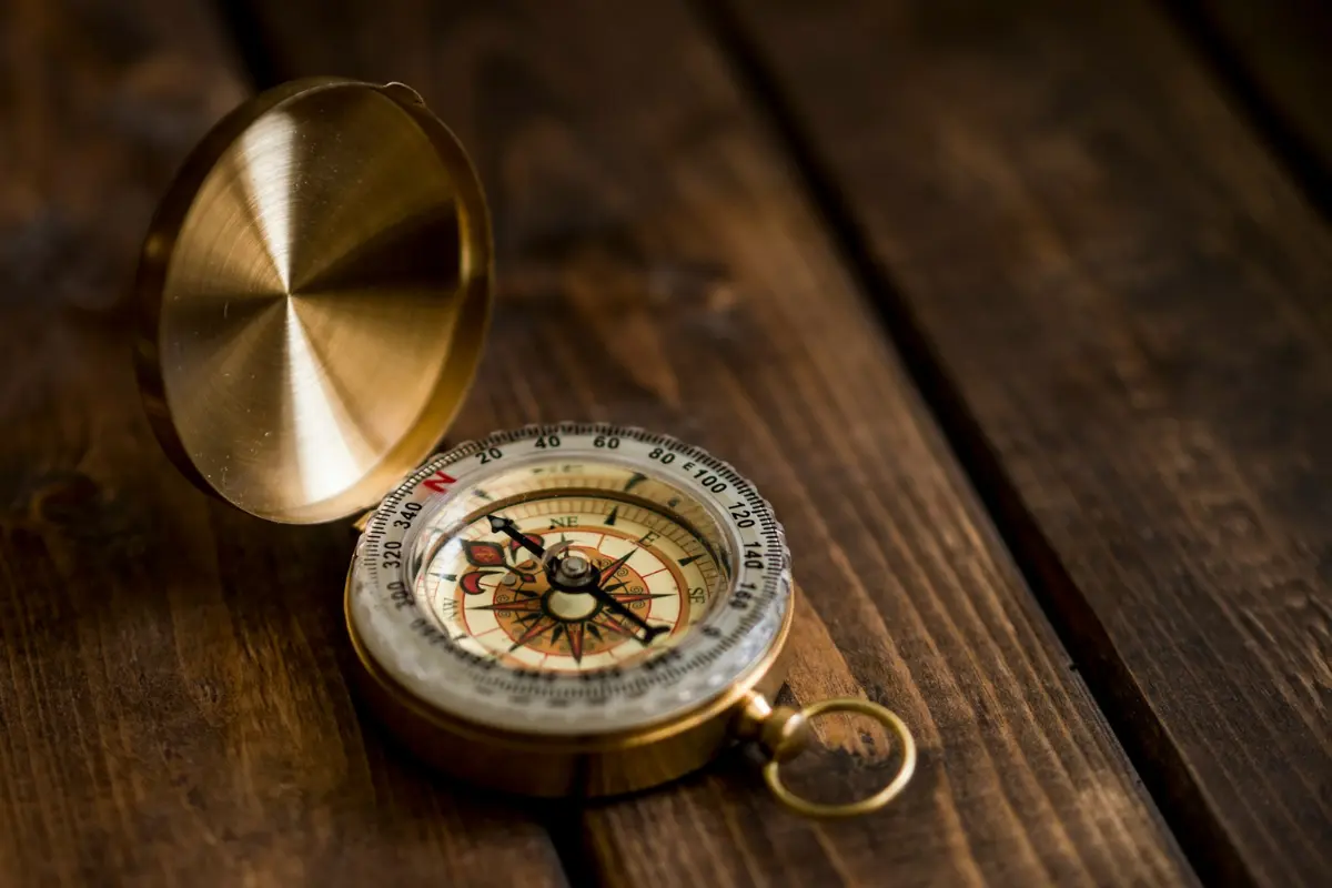 A vintage golden compass on a dark wooden surface, symbolizing the inner guidance used when learning how to raise your vibration through an emotional check-in.