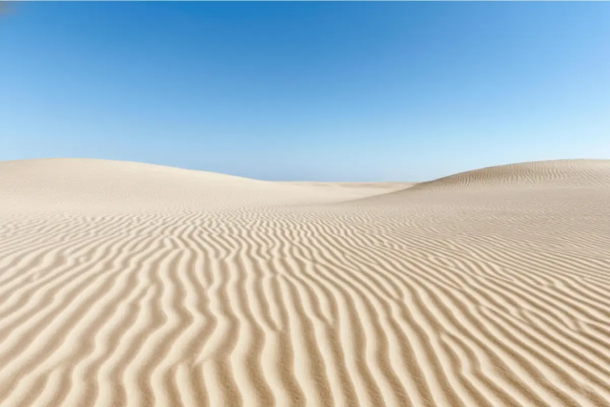 Rhythmic golden sand waves representing cymatics and frequency, symbolizing how a sound reset helps in learning how to raise your vibration.